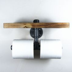 two rolls of toilet paper are hanging from a wooden holder on a white wall,