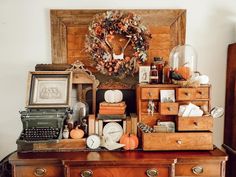 an old fashioned desk with many items on it and a wreath above the top shelf