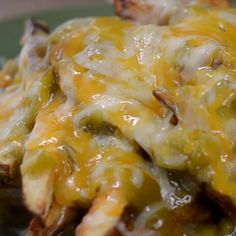 a green plate topped with cheesy potatoes covered in cheese