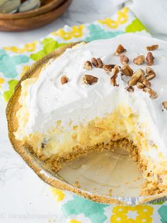 there is a pie with white frosting and nuts on the top, ready to be eaten