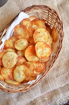 a basket filled with fried potatoes sitting on top of a table next to a cloth