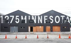 a black building with white lettering on the side and orange cones in front of it