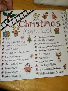 a christmas movie list is shown on a table next to a hand holding a pen