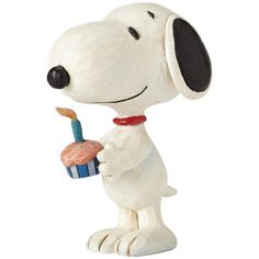 a figurine of a dog holding a cupcake with a candle in it's mouth