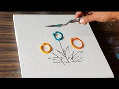 someone using scissors to cut out the flowers on a piece of paper with colored yarn