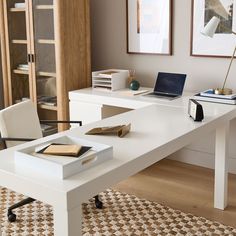 a white desk with a laptop computer on top of it next to a book shelf