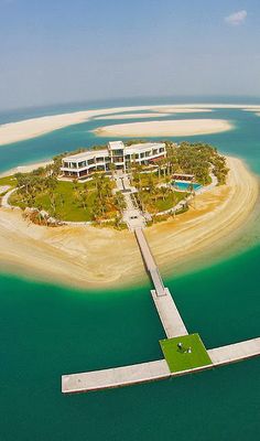 an island in the middle of the ocean with a building on it's side