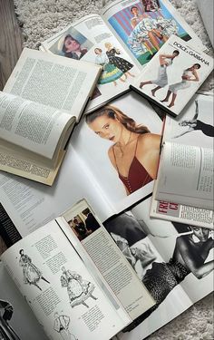 an open book sitting on top of a carpet covered floor next to pictures and books