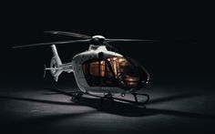 a white helicopter sitting on top of a black floor next to a light bulb in the dark