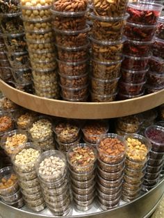 many different kinds of nuts in plastic containers on a display shelf at a grocery store