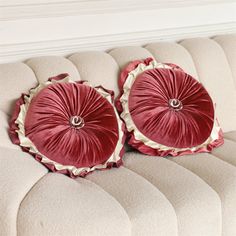 two red pillows sitting on top of a white couch