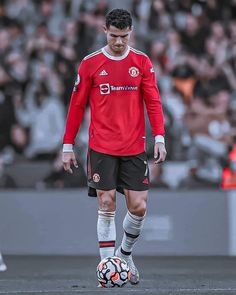 a soccer player in red and black is playing with a soccer ball on the field