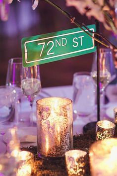 a table topped with candles and flowers next to a street sign that says 72nd st