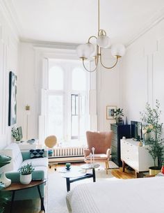 a living room filled with furniture and a white bed covered in pillows on top of a hard wood floor