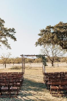 an outdoor ceremony set up with wooden chairs