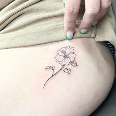 a woman's stomach with a small flower tattoo on her lower back side ribcage