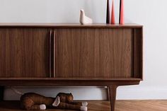 a wooden cabinet sitting on top of a hard wood floor next to a white wall