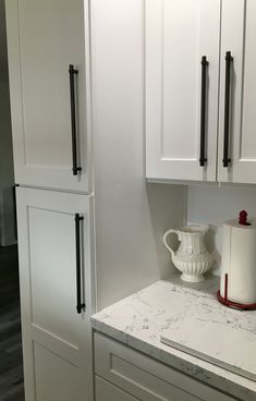 a kitchen with white cabinets and marble counter tops