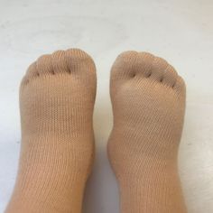 a person's feet with brown socks on top of white floor and bottom of the legs