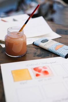 a jar of liquid sitting on top of a wooden table next to papers and a pencil