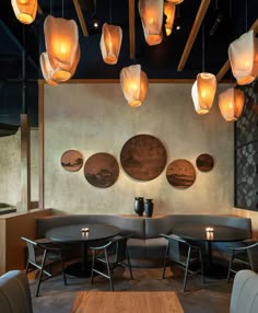 a restaurant with round tables and circular lights hanging from the ceiling above them is lit by candles