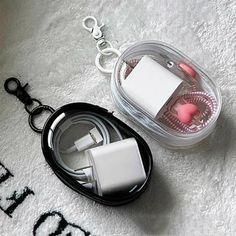 an apple charger and ear buds in a plastic case on a white carpeted surface