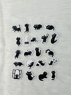 many cats stickers sitting on top of a white sheet with black cat silhouettes