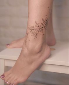 a woman's foot with a branch tattoo on it