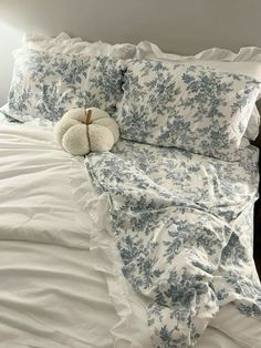 a bed with blue and white comforter, pillows and two stuffed animals on it