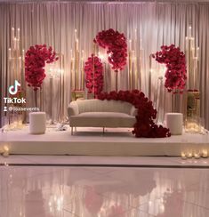 a white couch sitting in front of a stage with red flowers on it