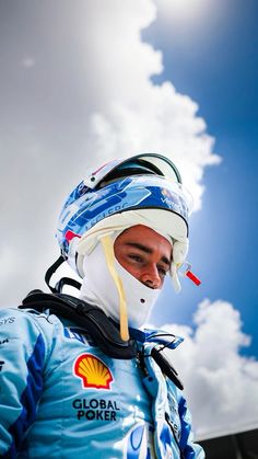 a man wearing a blue jacket and white face mask while standing in front of a cloudy sky