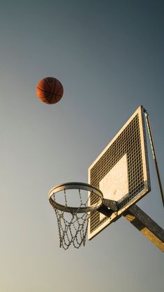 a basketball flying through the air next to a basket on top of a basketball court