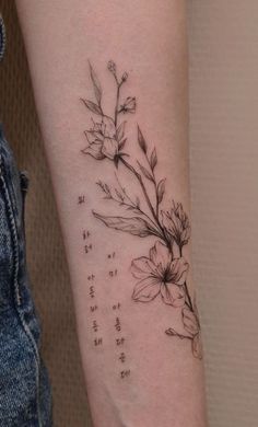 a woman's arm with flowers and numbers tattooed on the back of her arm