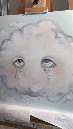 a painting of a cloud with two eyes and raindrops on it, in front of a easel