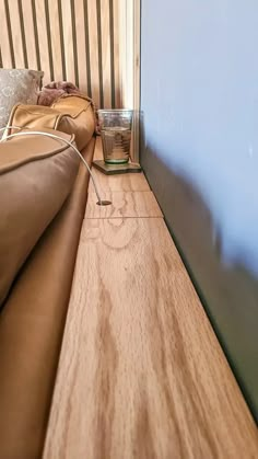 there is a glass sitting on the edge of a bed that has been made into a headboard