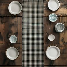 the table is set with white dishes and place settings on it, along with plaid napkins