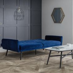 a living room with grey walls and wood flooring, two blue couches and a coffee table