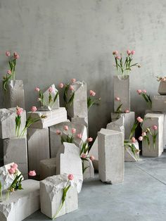 several cement blocks with flowers in them sitting on the concrete floor next to each other