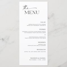 a white menu card with the word, the menu on it in black ink is sitting on a marble surface