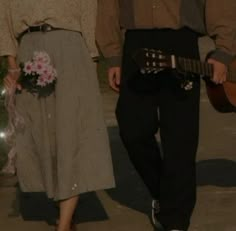 a man and woman are walking down the street with flowers in their lap holding guitars