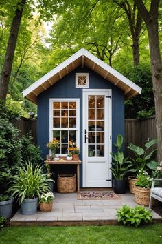 a small blue shed with potted plants in front of it and the door open