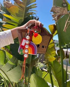 a hand holding a purse with charms attached to it