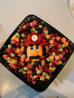 a tray filled with fruit topped with a face