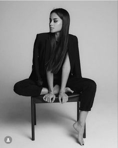 a woman sitting on top of a chair with her legs crossed in front of her face