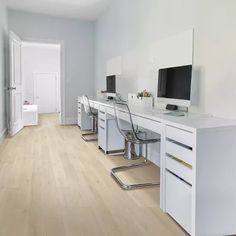 there are three computer desks and two chairs in the room with wood flooring