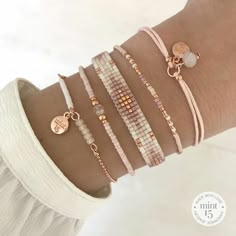 the bracelets are stacked on each other with gold charms and beads in different colors