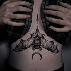 a woman's stomach with a bat tattoo on her belly and the moon above it