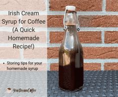 a glass bottle filled with liquid sitting on top of a table next to a brick wall