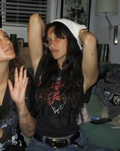 two women sitting on a couch with their hands in the air