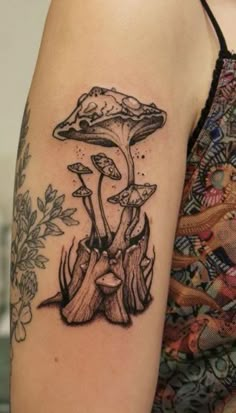 a woman's arm with tattoos on it and mushrooms growing out of the ground